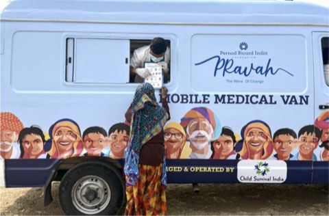 A woman at the counselling window of the Arogyam mobile medical van, being shown a health information card by the clinician inside.