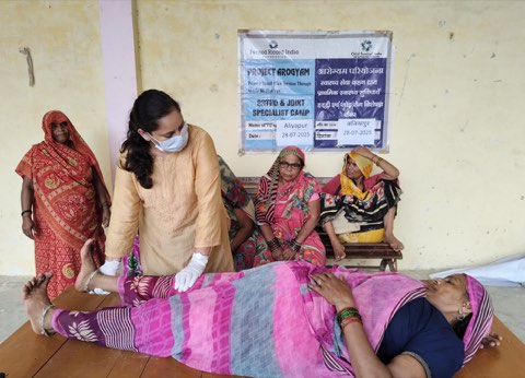 An orthopaedic and joint specialist camp at Aliyapur: a physiotherapist assessing a patient's leg while others wait.