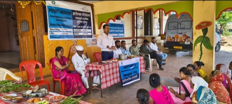 A nutrition demonstration and counselling session, the mobile medical van parked alongside.
